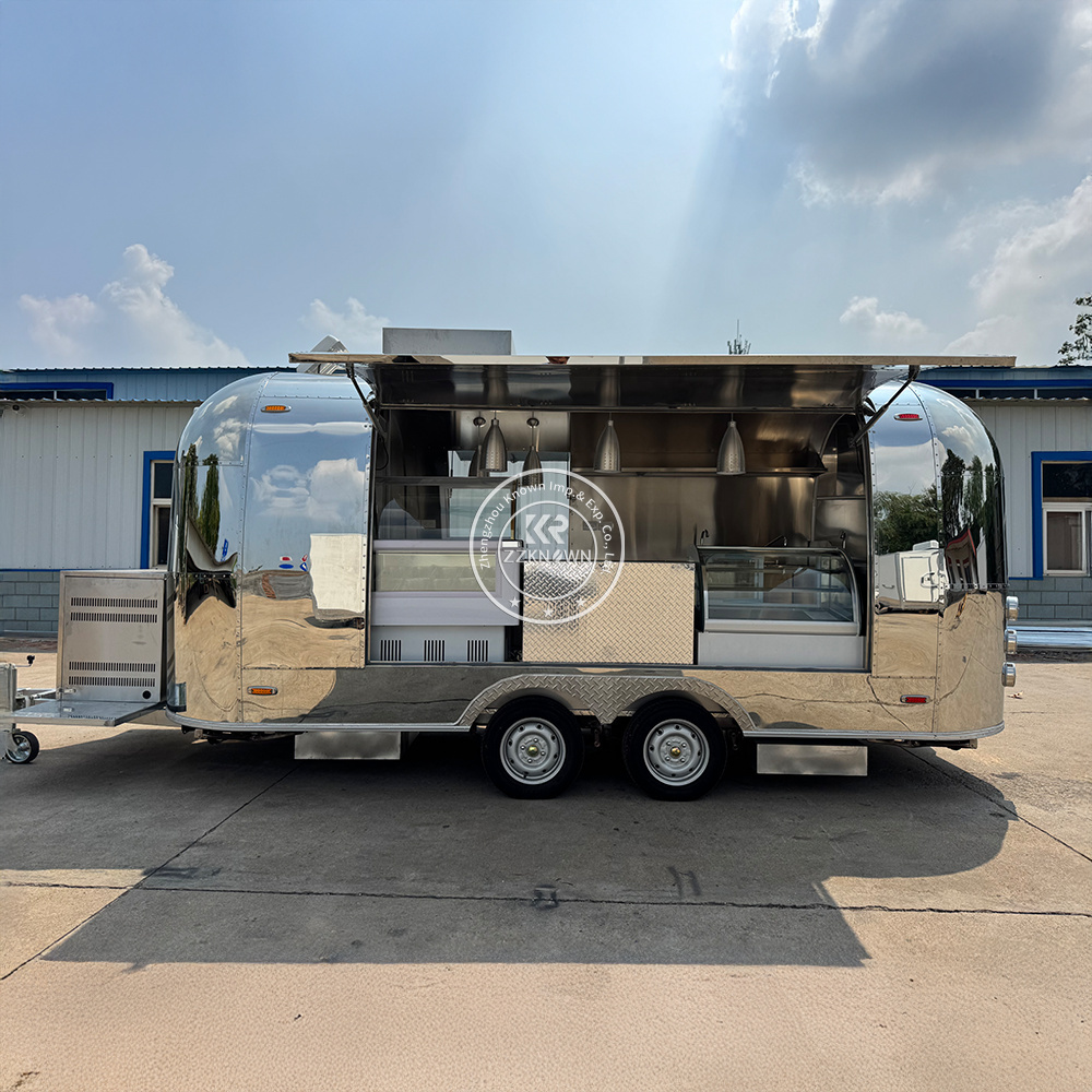 Airstream-style food trailer side view with two large electric lift serving windows open, showing food display cabinets